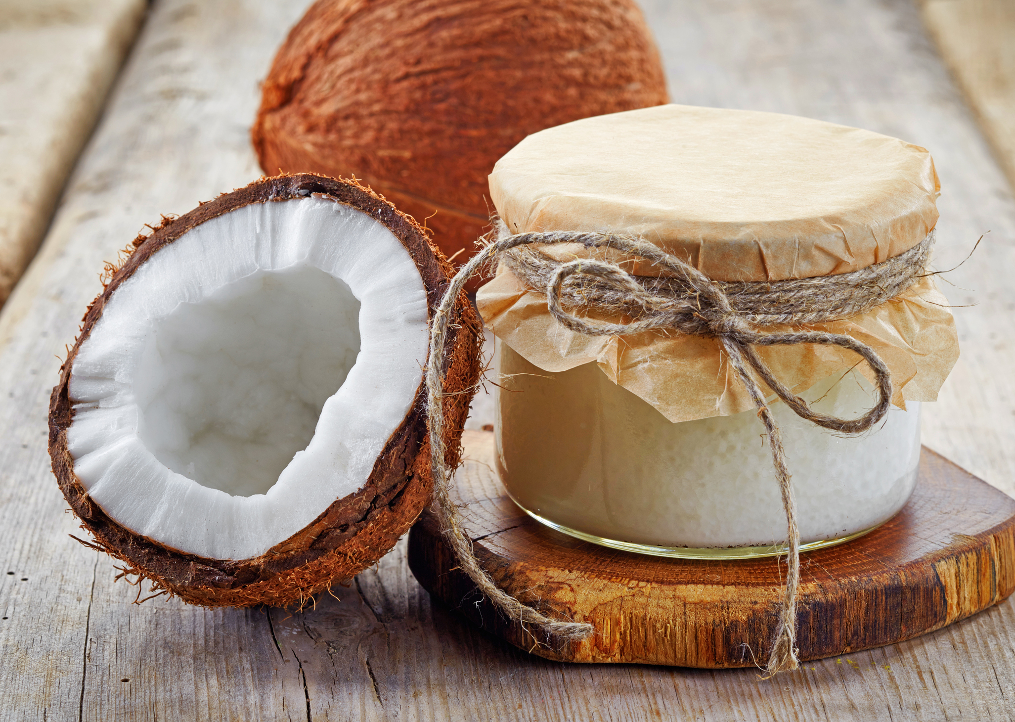 jar of coconut oil and fresh coconuts on wooden table